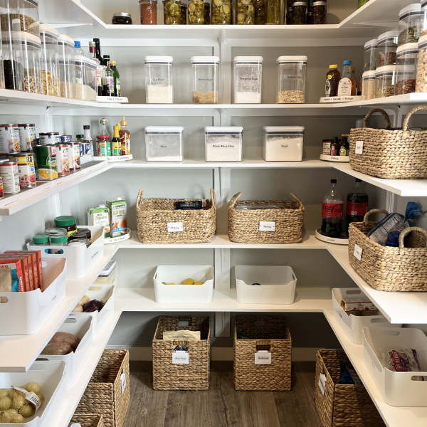Step-in pantry organized with wrap-around shelves, woven baskets, and clear containers using vertical space