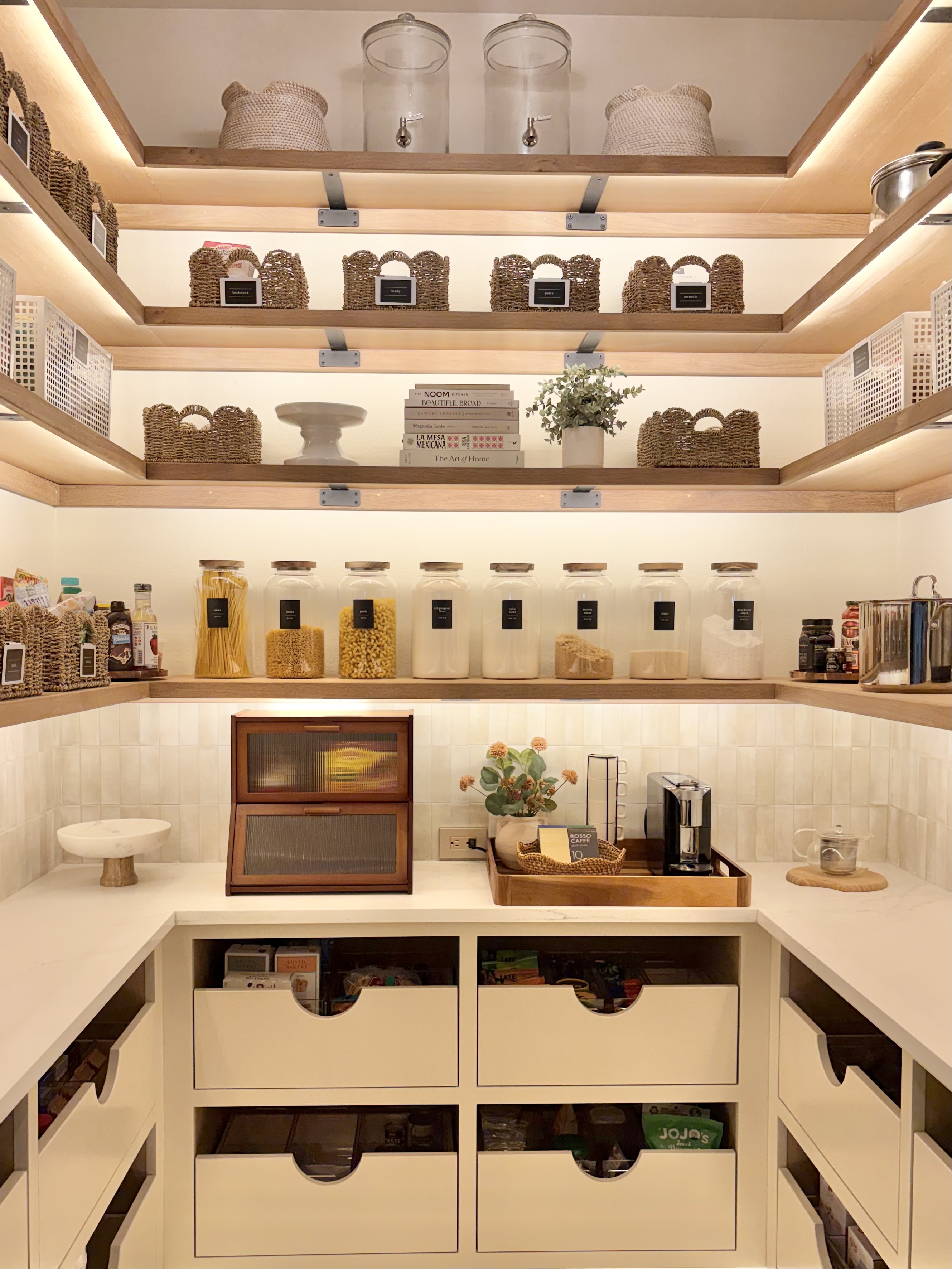 Organized walk-in pantry in Austin with woven baskets, labeled glass canisters, and pull-out drawers