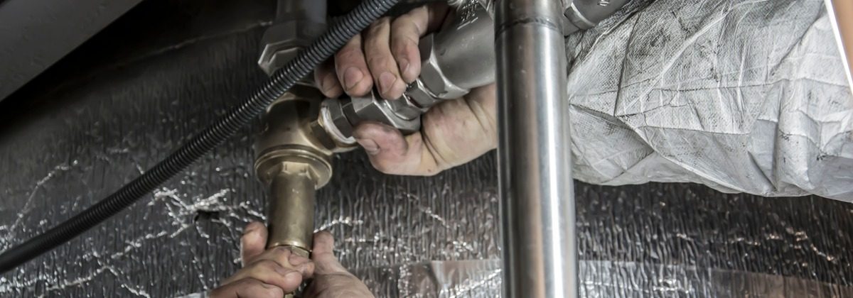 Plumber tightening a sink trap fitting with a wrench