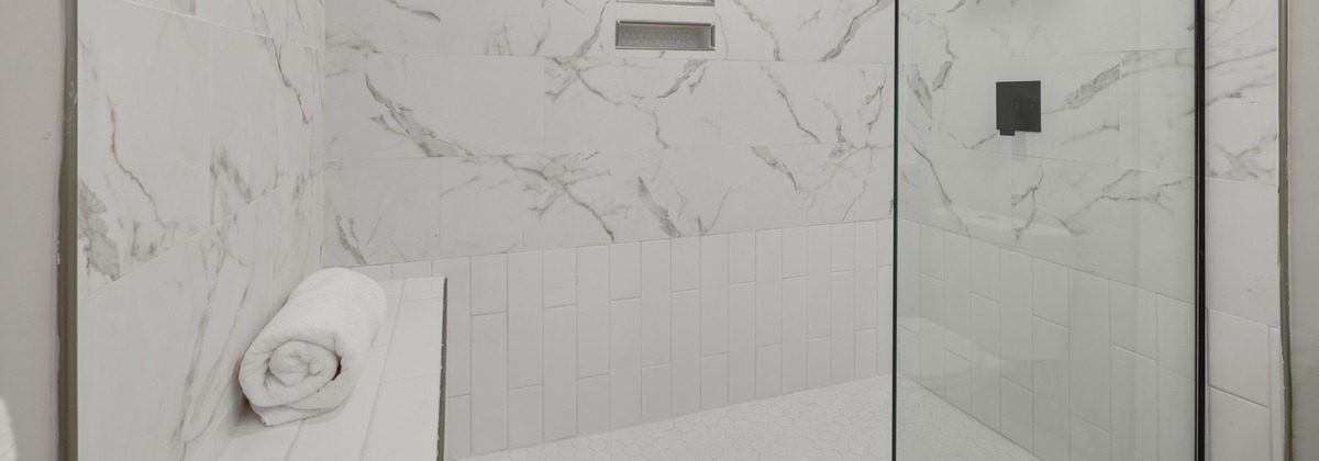 Built-in tiled bench in a marble walk-in shower