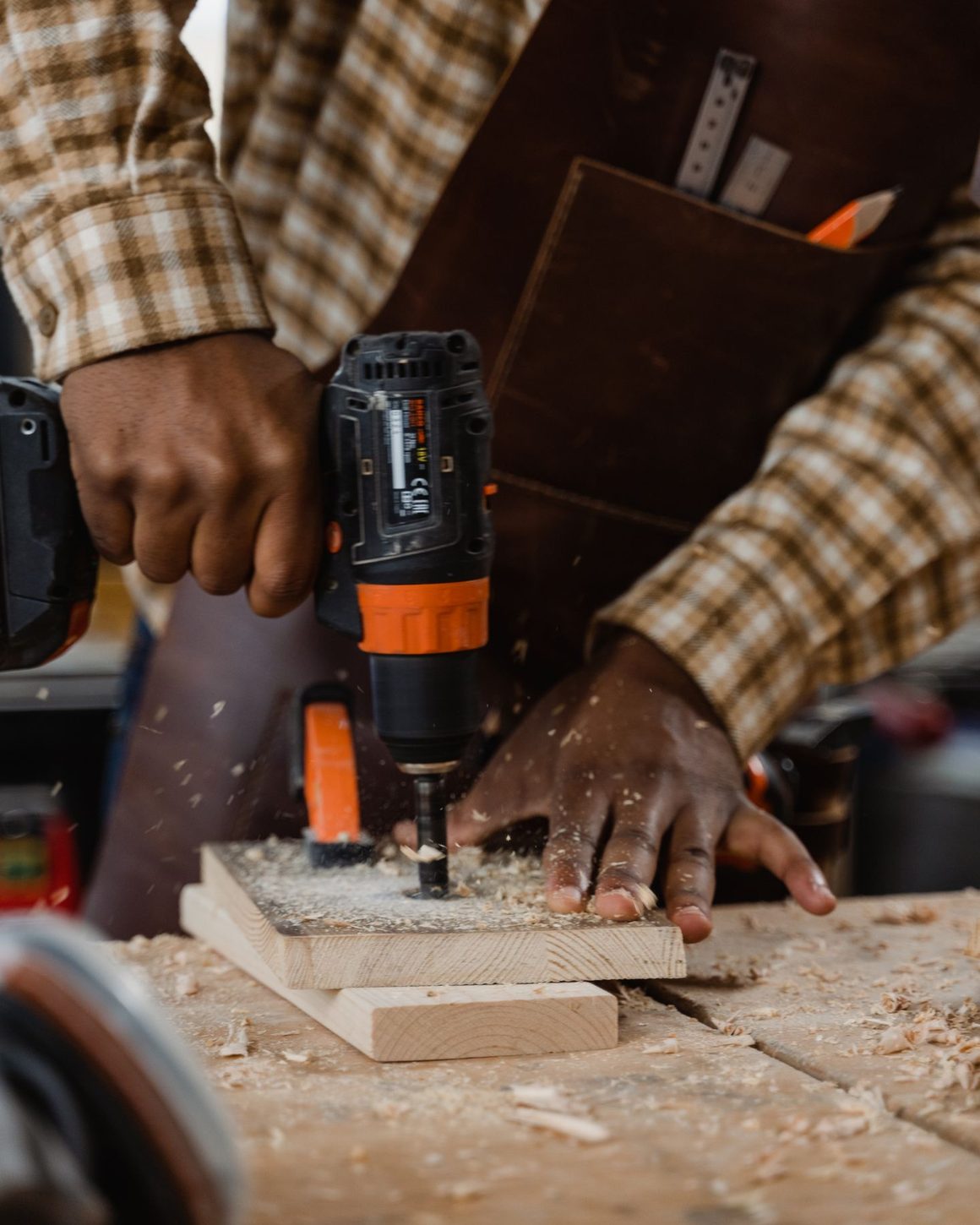 Tradesperson's hands drilling into timber on a workbench