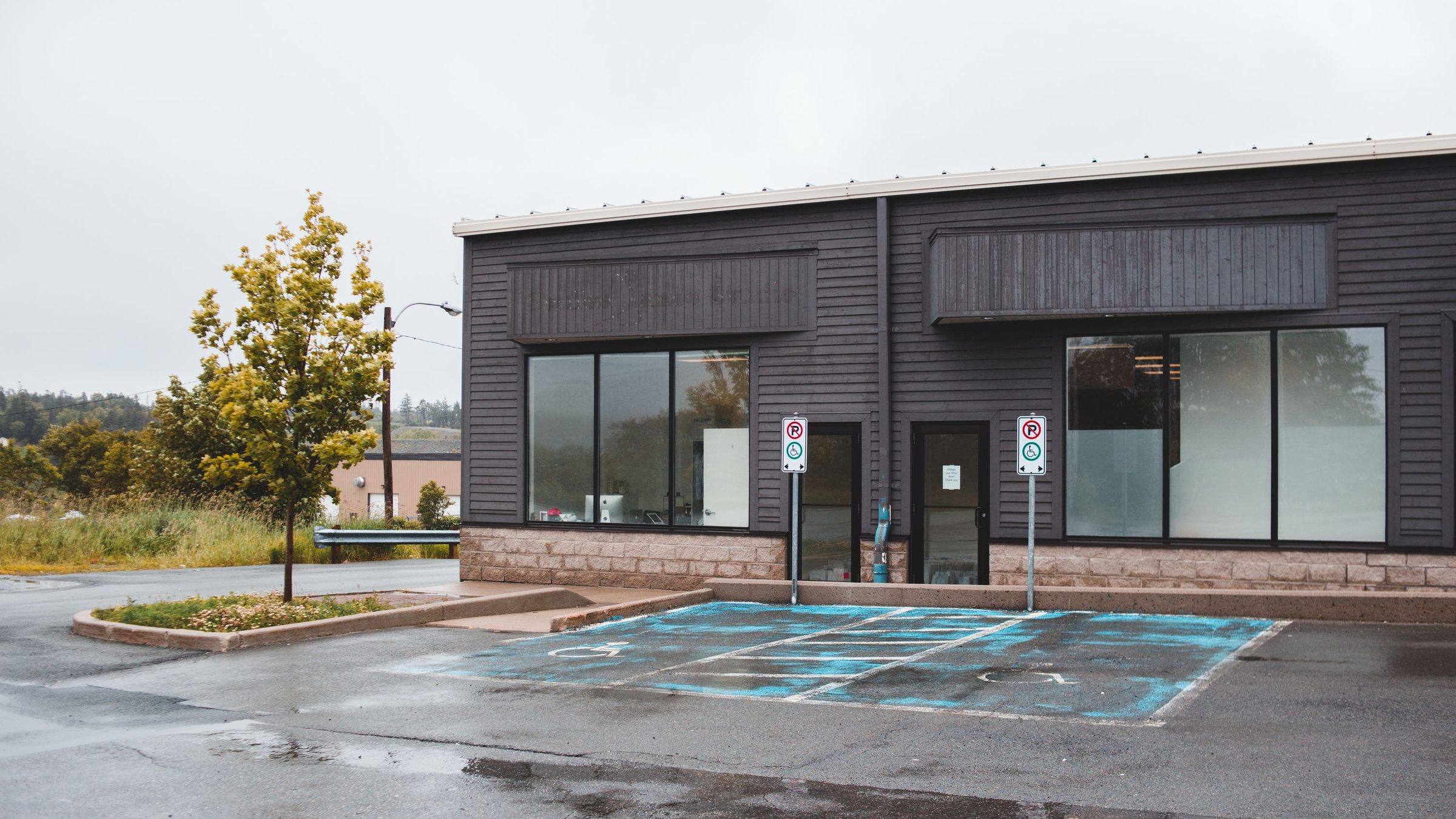 Single-storey commercial building frontage with glass storefronts on an overcast day