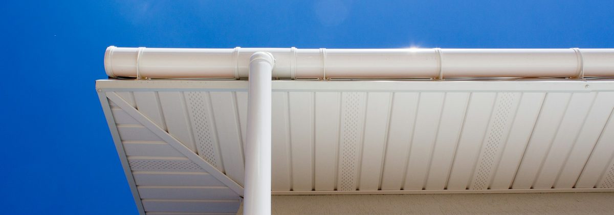 Underside of new white vented soffit and fascia with an eavestrough