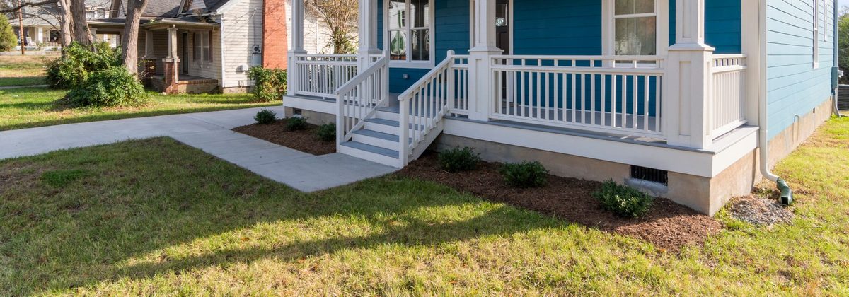 Porch steps with white handrails on a well-kept house