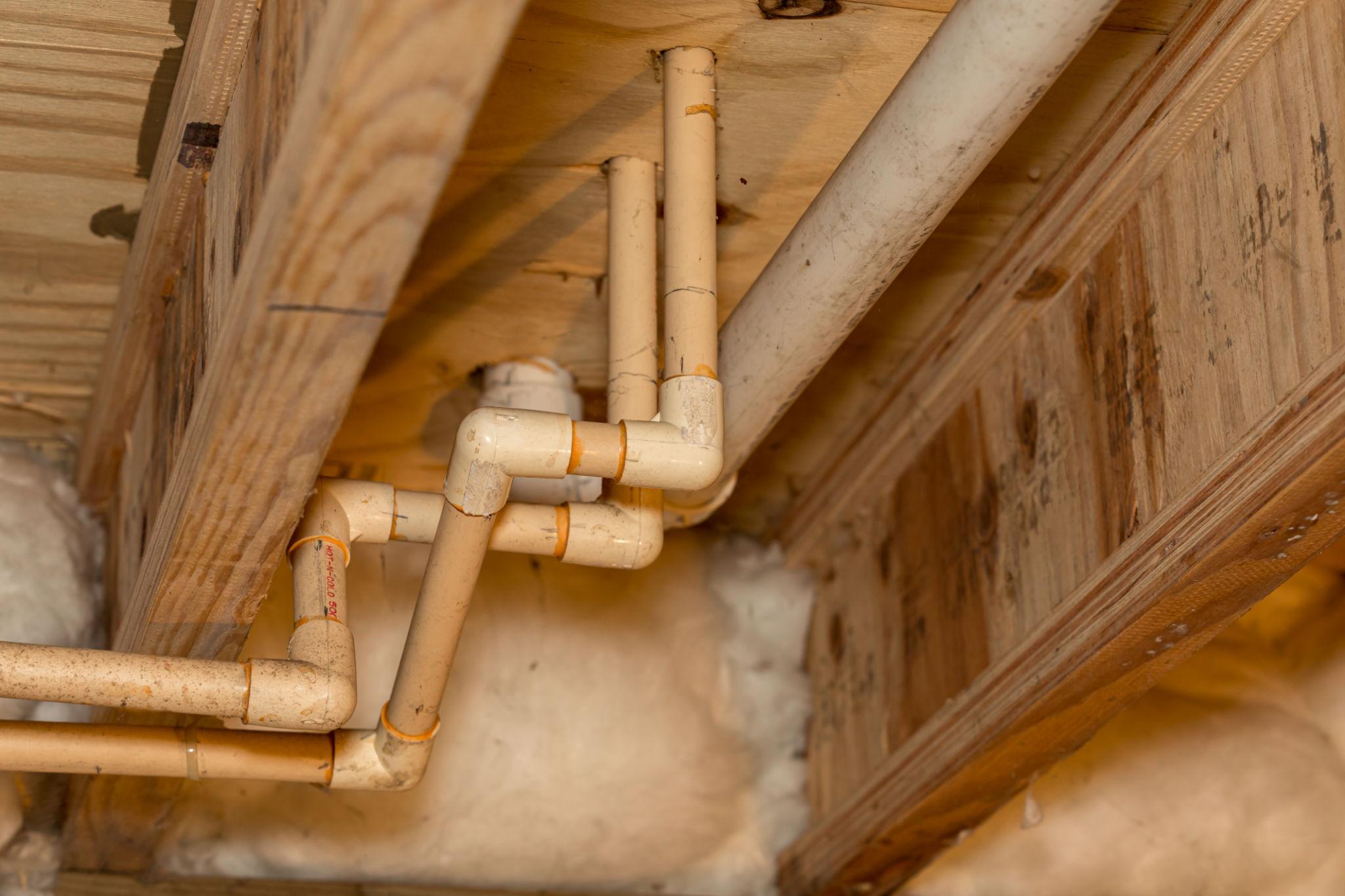 Plumbing lines running beneath a home through a residential crawl space.