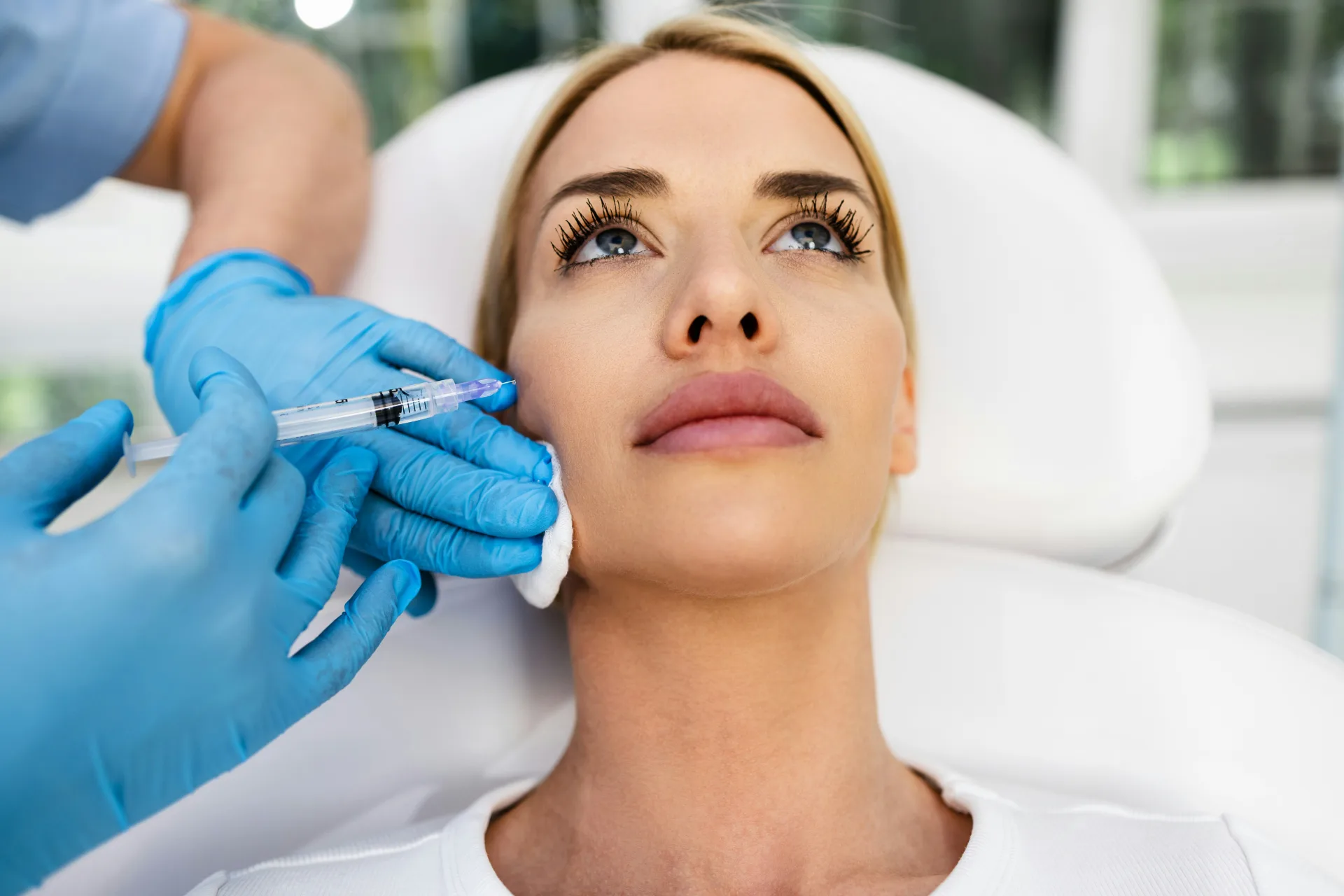 Woman receiving a precise filler injection near the cheek