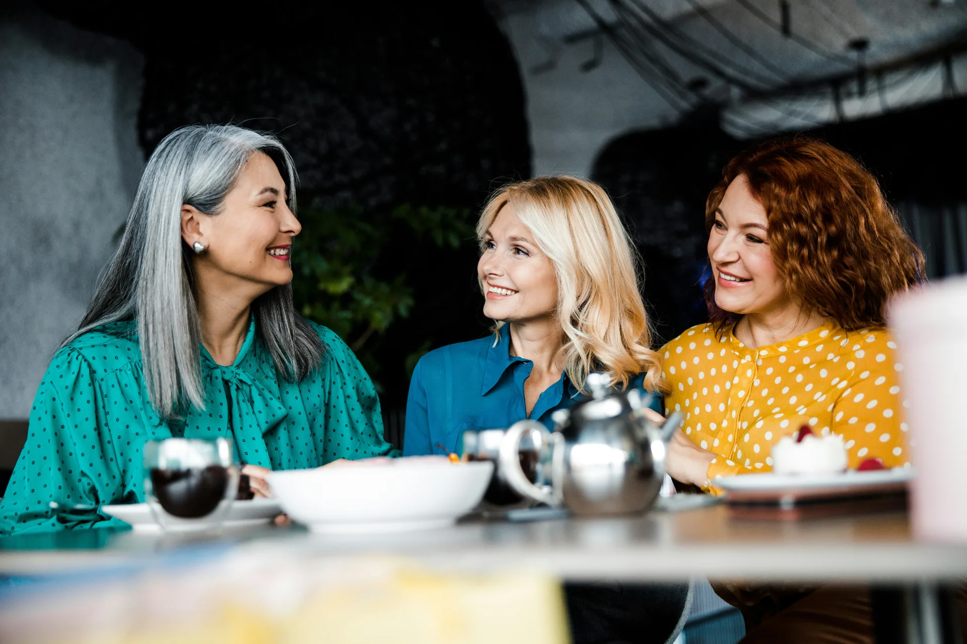 Three women laughing together over coffee