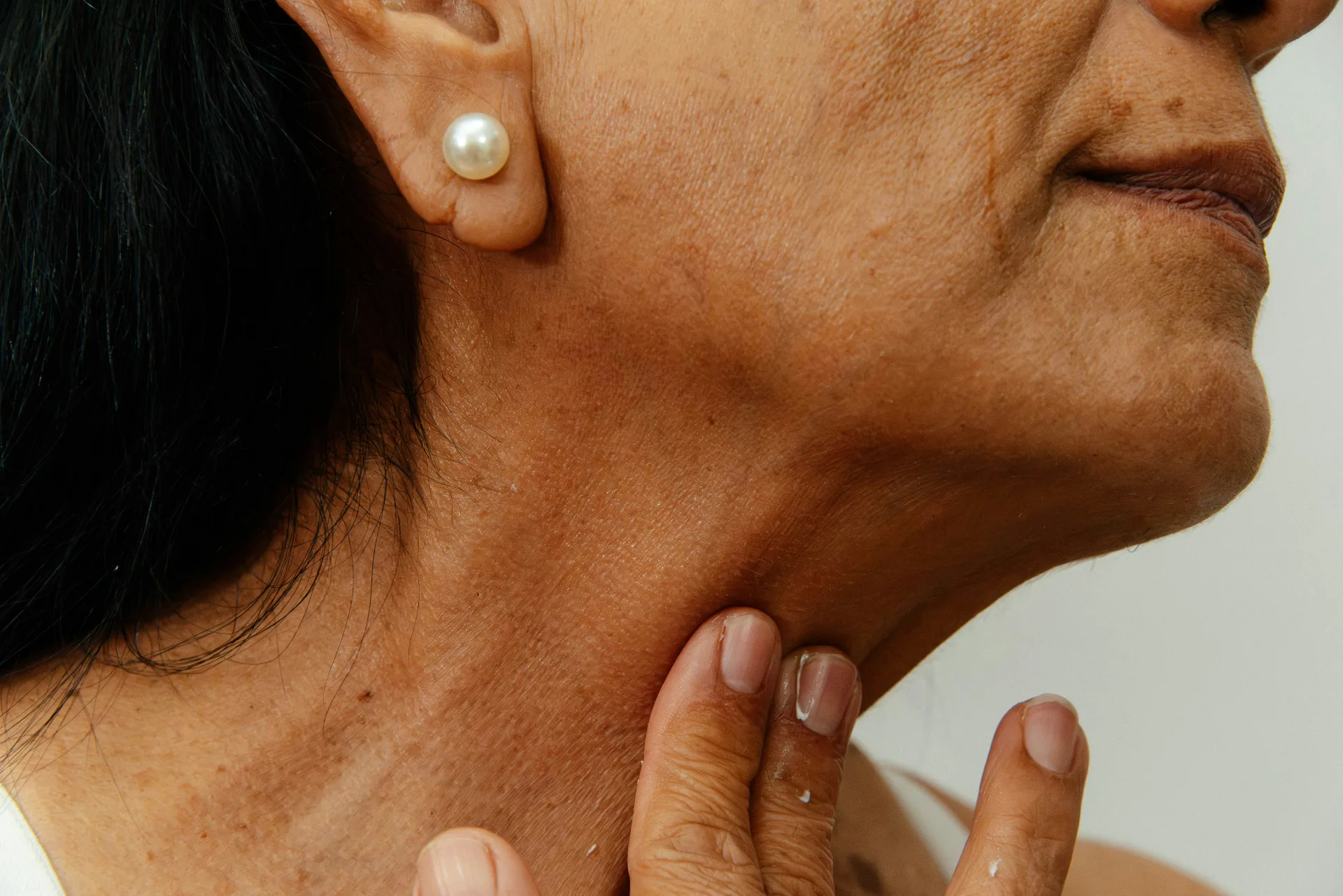Mature woman touching the smooth skin of her neck
