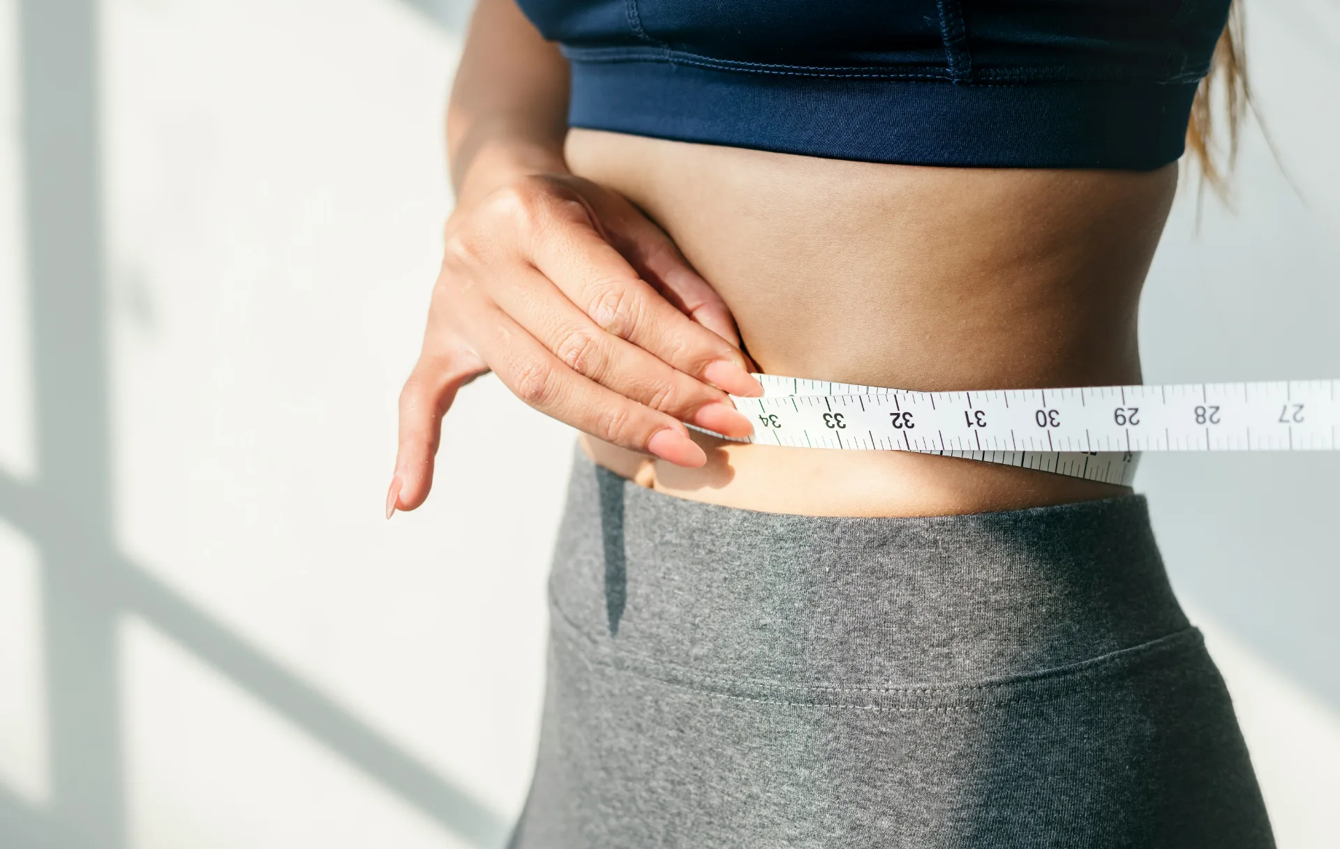 Woman measuring her waist during her weight loss progress