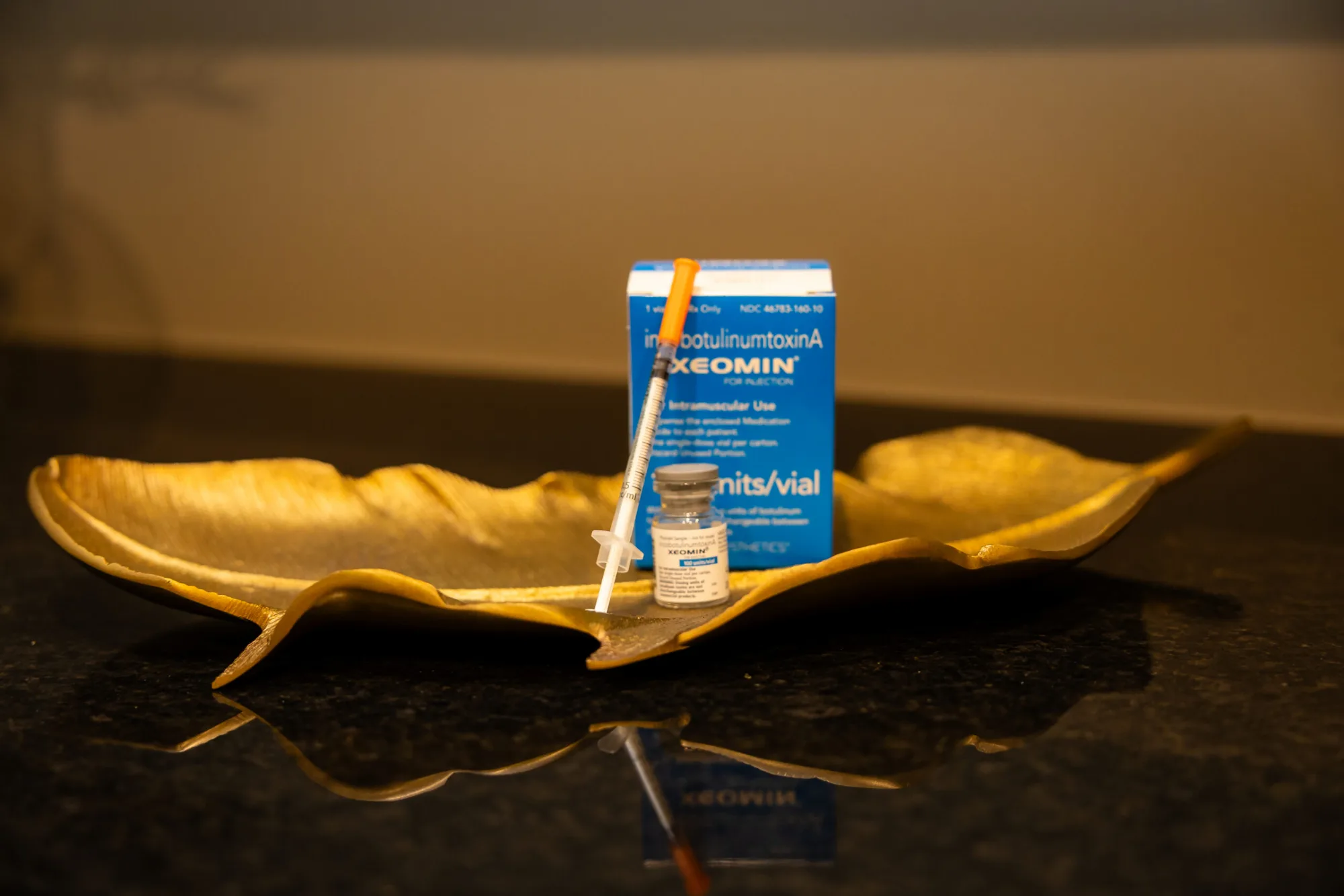Injectable medication vial and box on a gold leaf tray