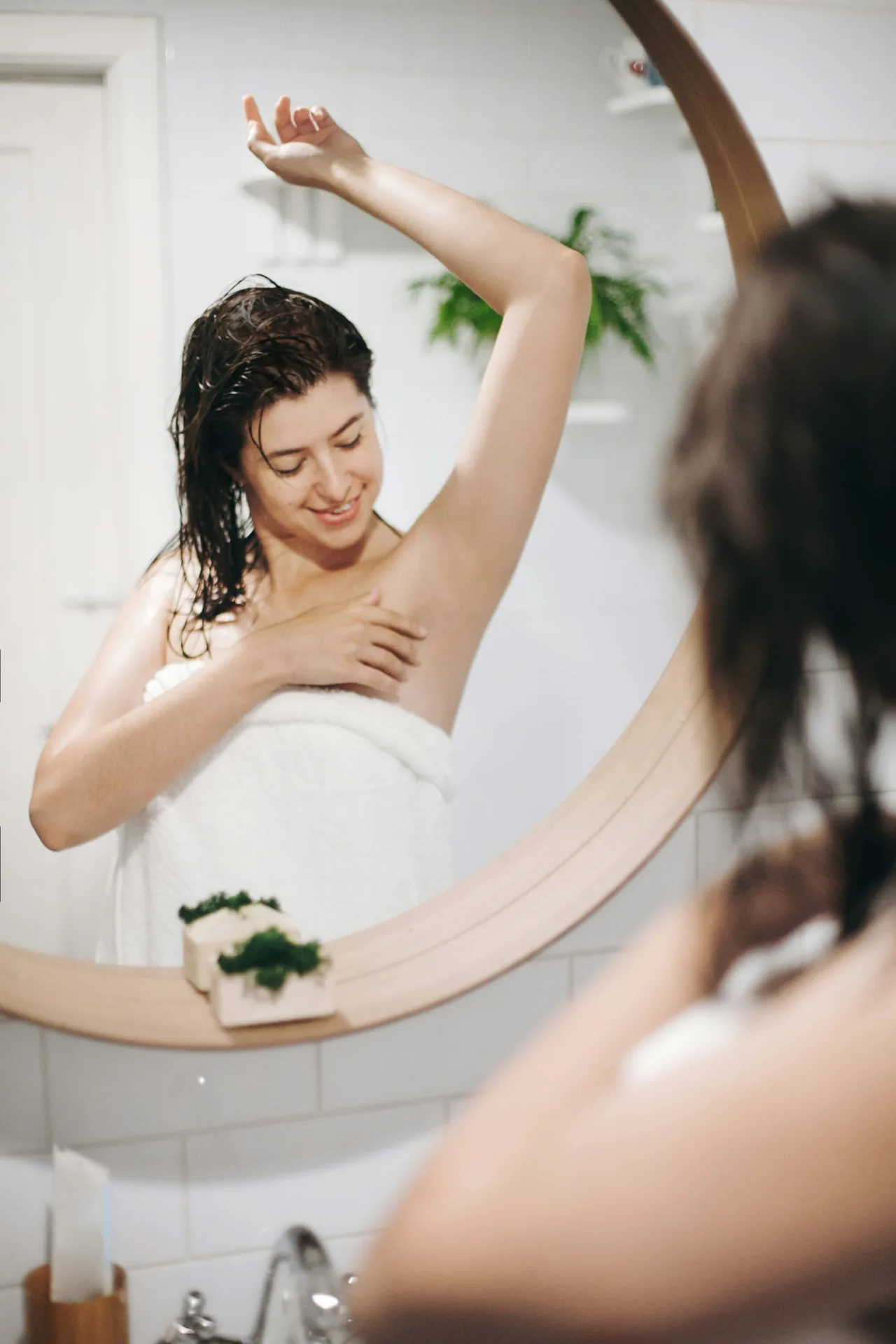 Woman in a towel enjoying smooth underarms after waxing