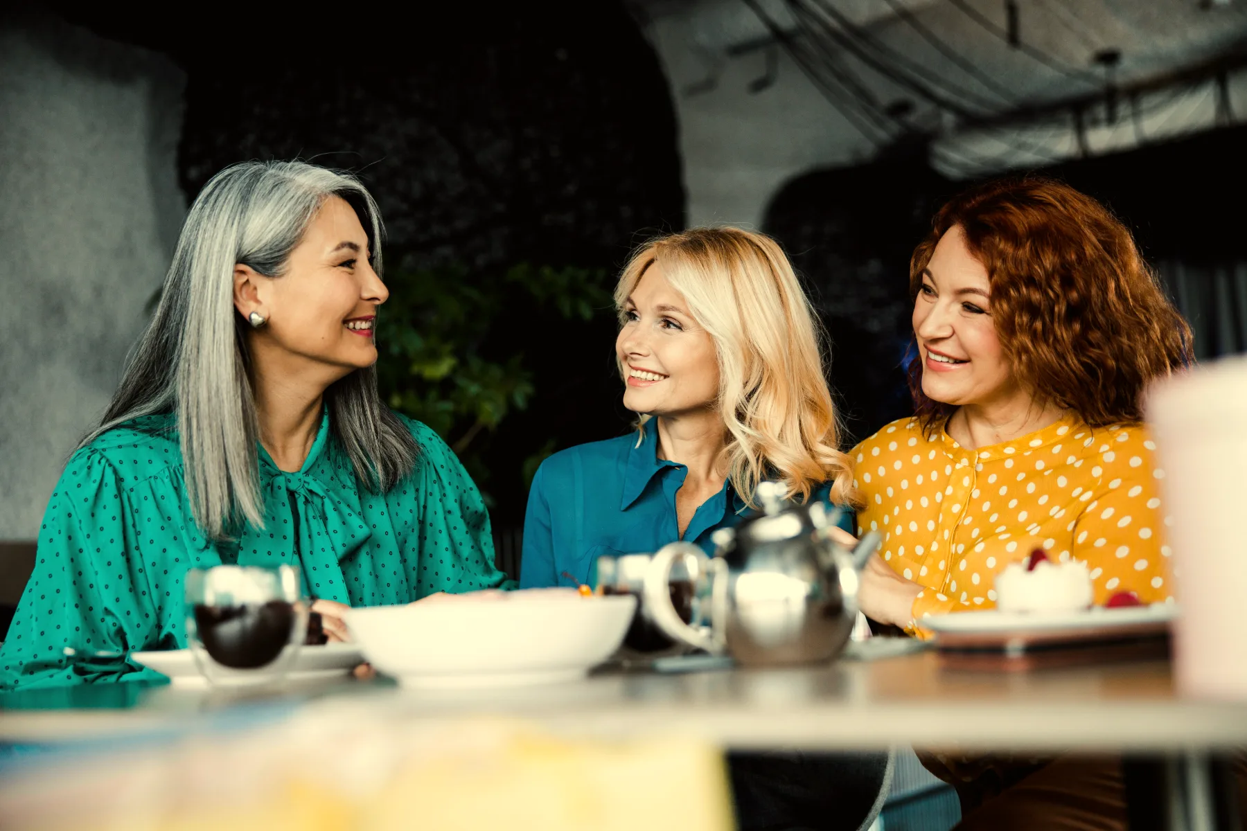 Three women friends laughing together over lunch