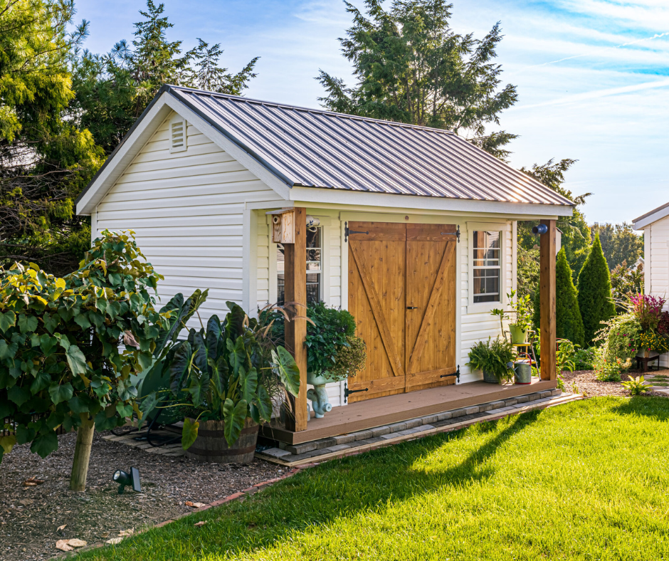 White garden shed with a wooden door, surrounded by greenery and flowers, emphasizing a serene outdoor space for marketing strategy consultations.