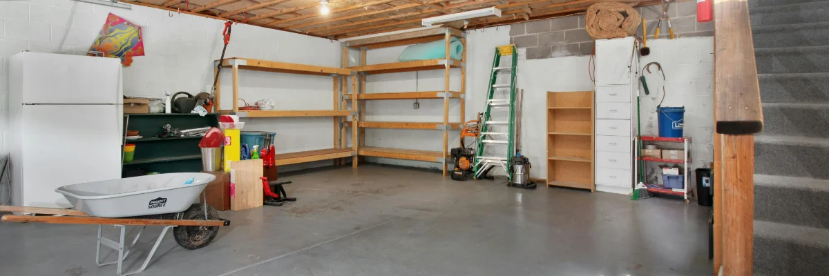 Spacious basement garage with shelves, ladder, and storage tools. Spacious basement garage with shelves, ladder, and storage tools.
