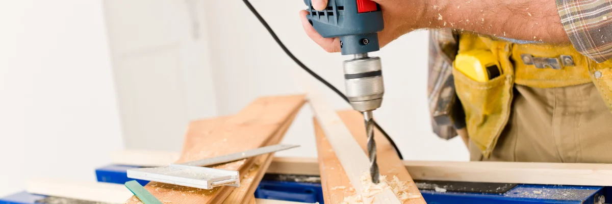 Carpenter drilling hole into wooden board with power drill. Carpenter drilling hole into wooden board with power drill.