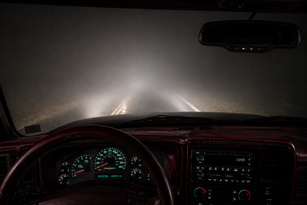 View from inside a Suburban driving through dense fog on a winding road with only a few feet of visibility.