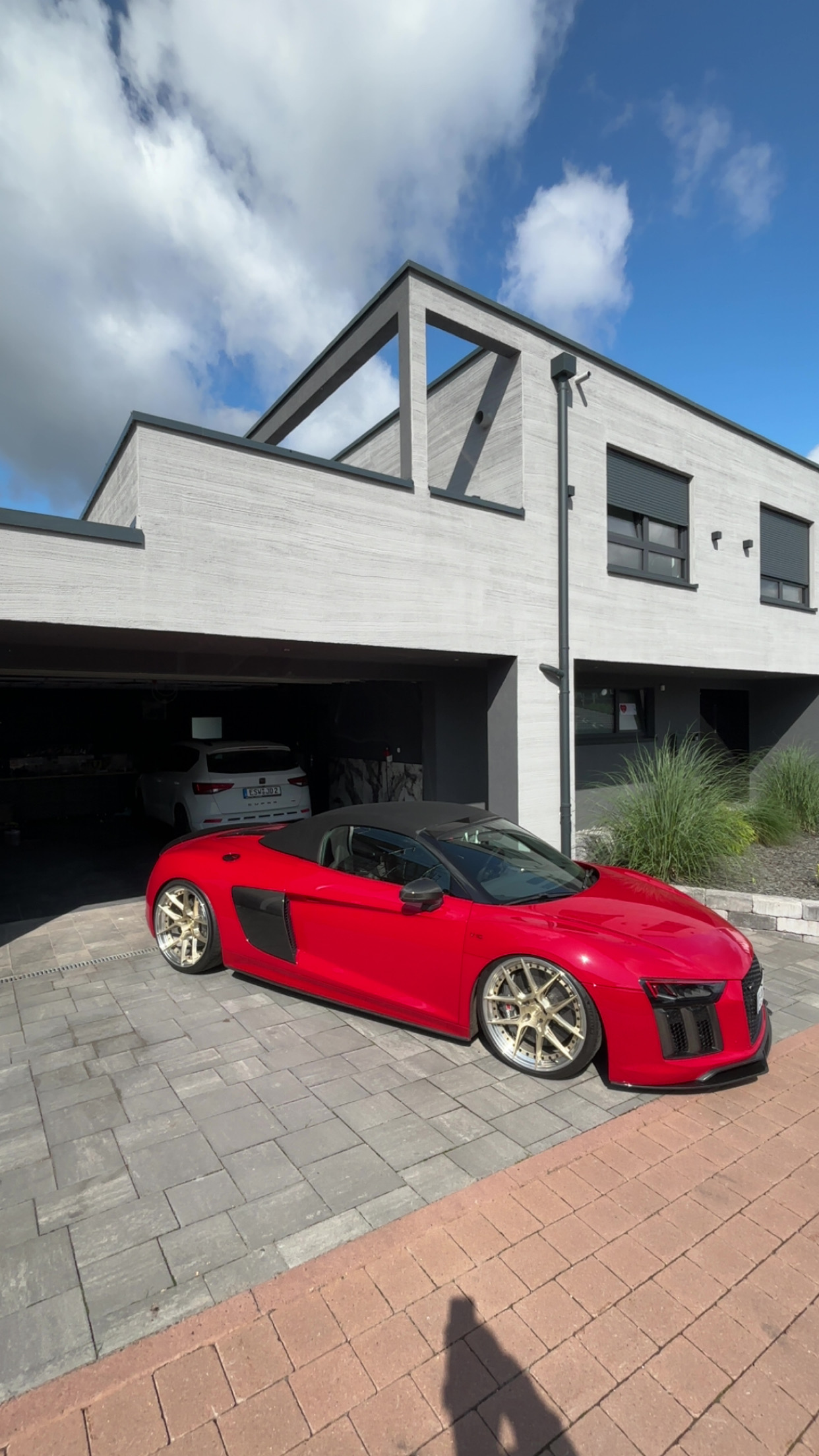Audi R8 Spyder in rot mit dicken Felgen nach einer Aufbereitung in der Sonne vor einem schönen Haus.