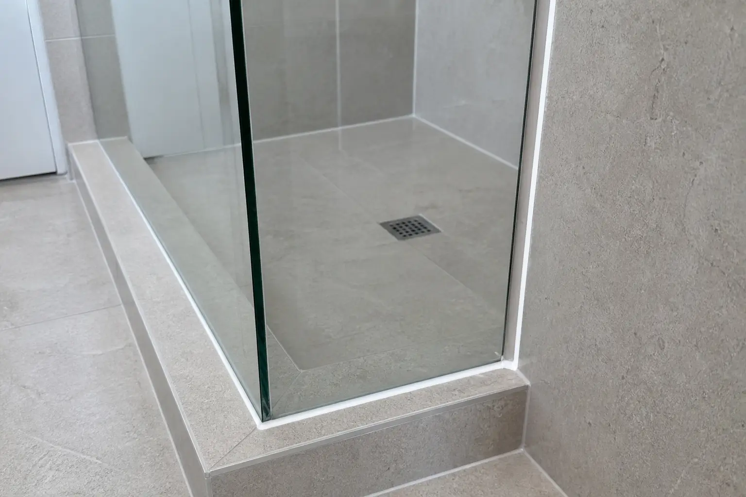 Example neat silicone seals around a frameless glass shower