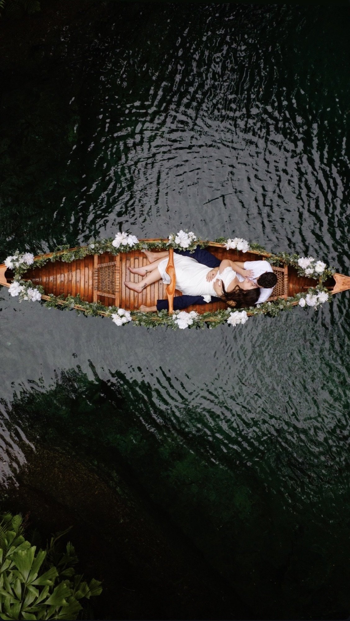 A couple in a flower-decorated canoe on their wedding day