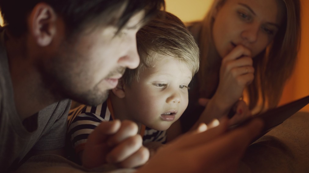 Family using a screen at night, a common contributor to dry eyes