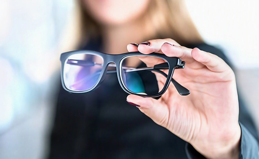 Hand holding glasses with multifocal lenses Hand holding glasses with multifocal lenses