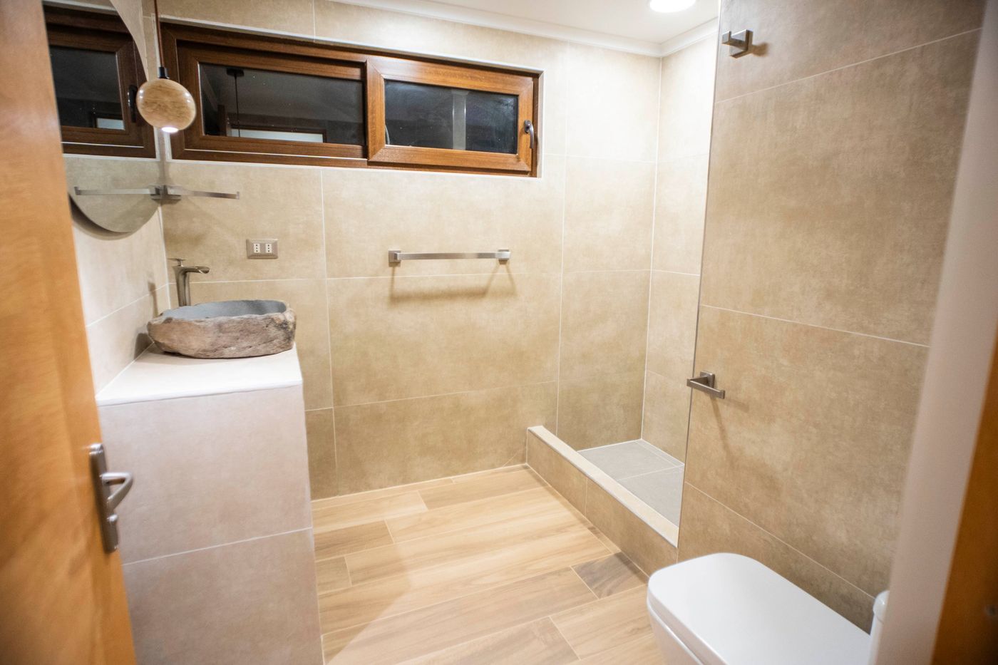 Baño de visitas de Casa Arrayán con lavamanos de piedra y revestimiento de porcelanato