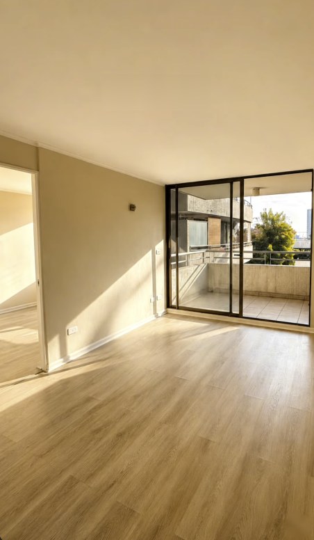 Living del departamento en Las Condes con piso nuevo y ventanal hacia la terraza