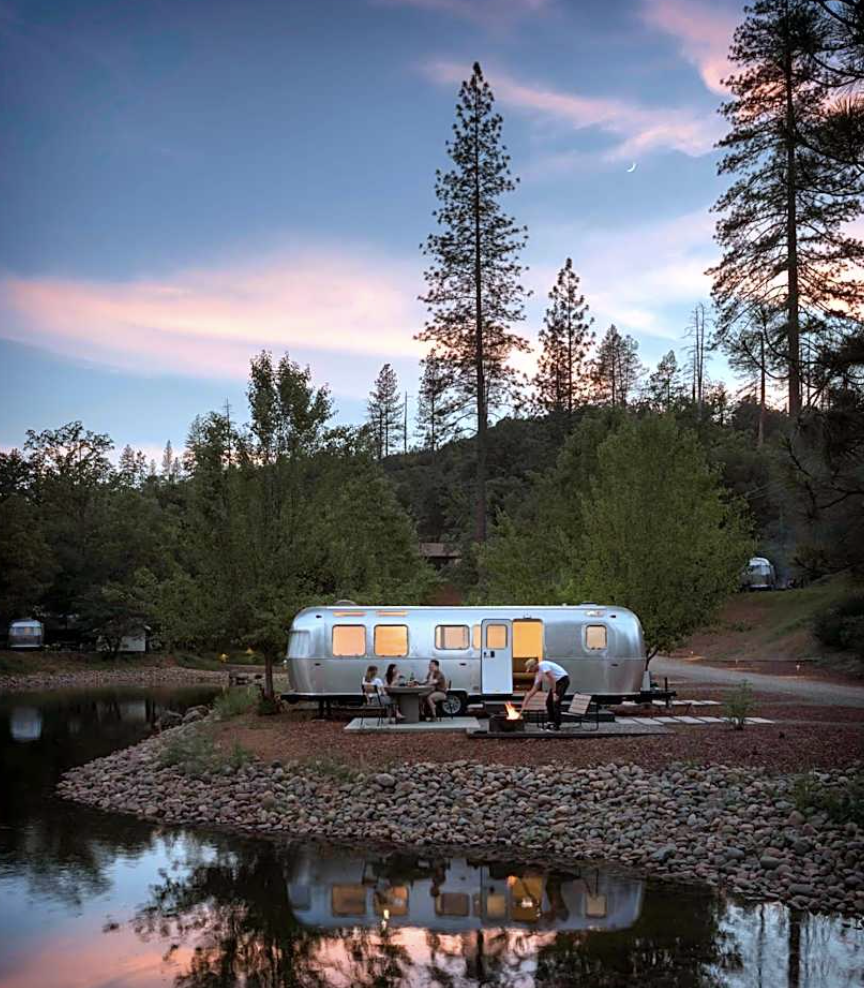 Airstream glowing at dusk in the forest