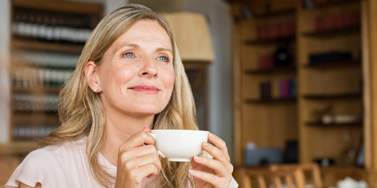 Woman over 50 smiling with a coffee in a café, feeling relaxed and confident Woman over 50 smiling with a coffee in a café, feeling relaxed and confident