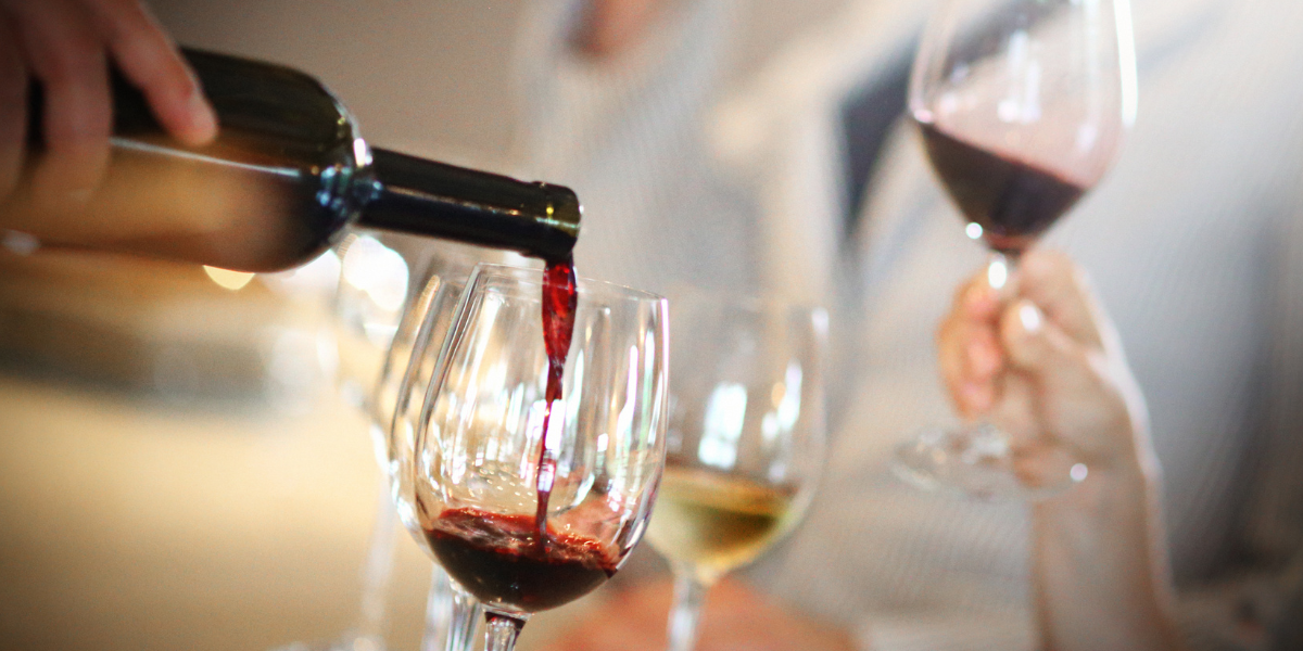 Wine being poured into glasses at a friendly social event for people over 50 Wine being poured into glasses at a friendly social event for people over 50