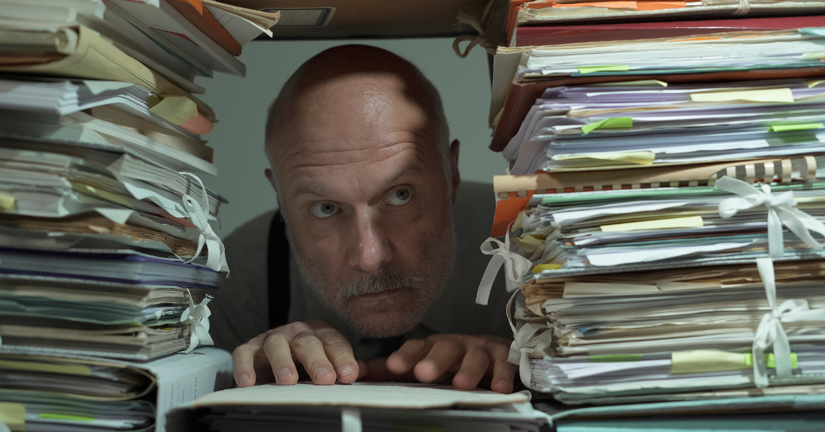 Man buried in paperwork showing disorganised bookkeeping and financial overwhelm in business