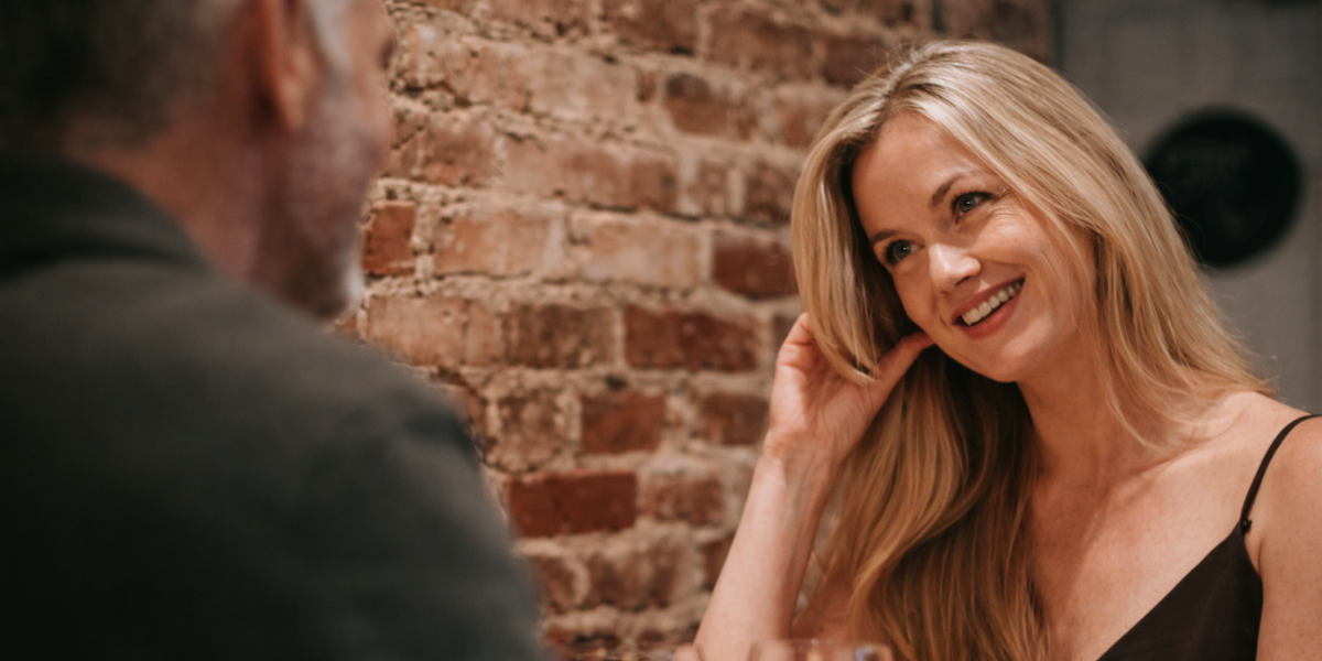 Woman over 50 smiling and gently playing with her hair while chatting, showing relaxed and natural flirting Woman over 50 smiling and gently playing with her hair while chatting, showing relaxed and natural flirting