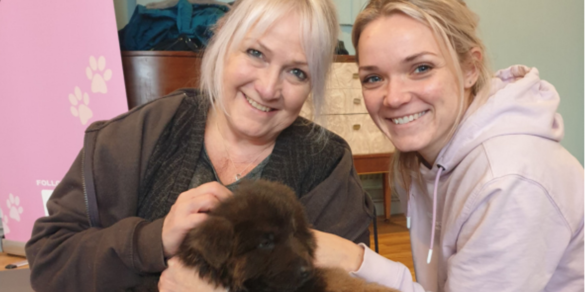 Mother and daughter smiling together while holding a puppy, showing connection, warmth and happiness