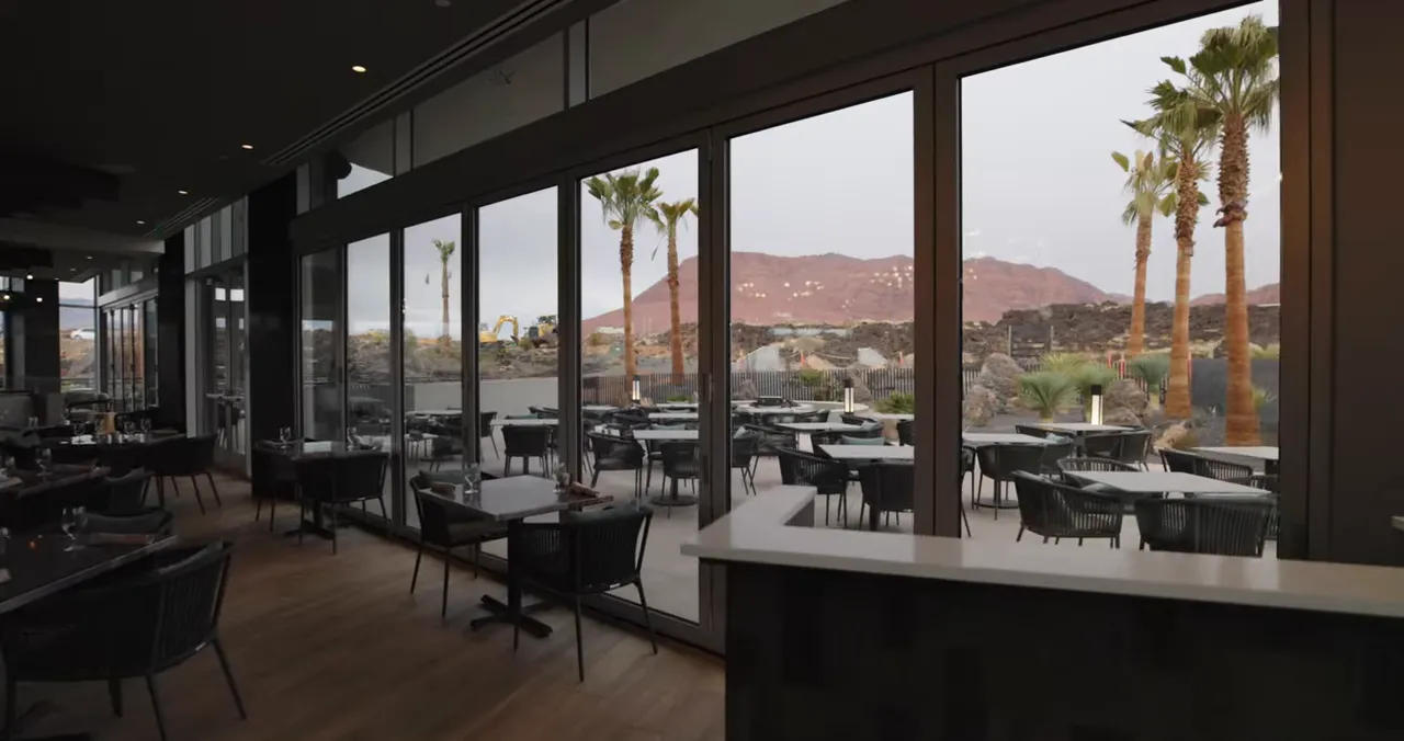 Dining room windows overlooking patio seating, palm trees, and red mountains