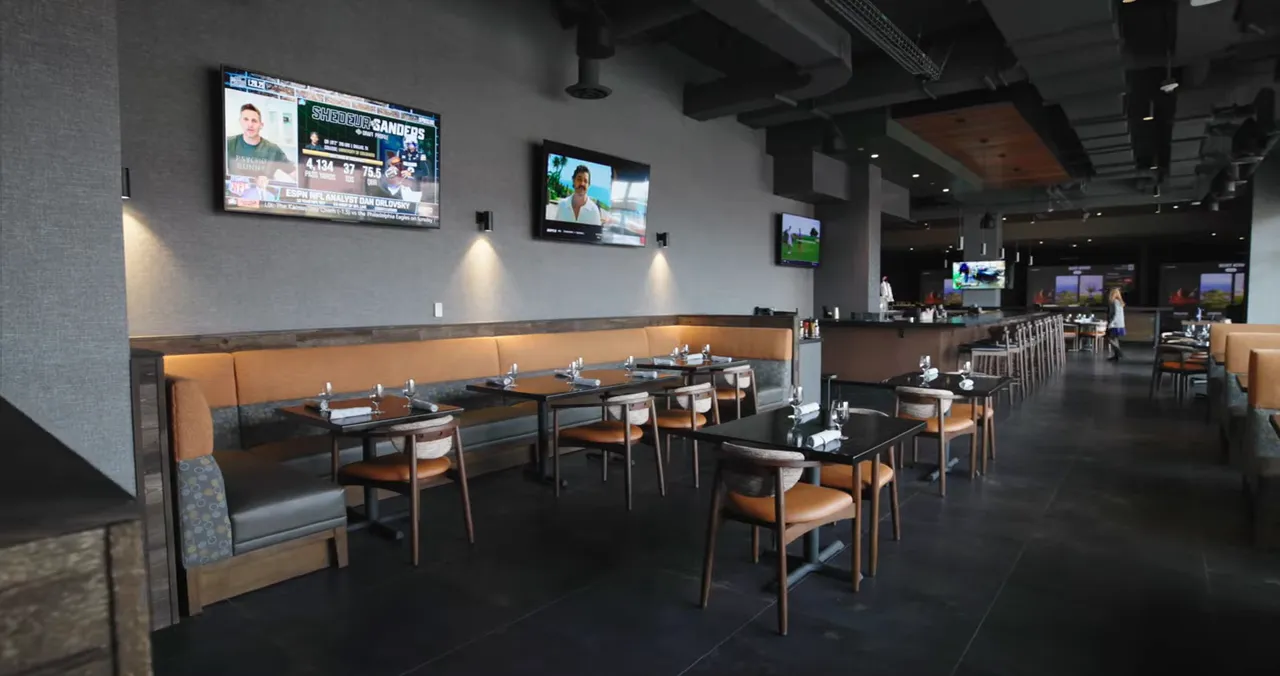 Sports bar dining room with televisions along the wall and tables