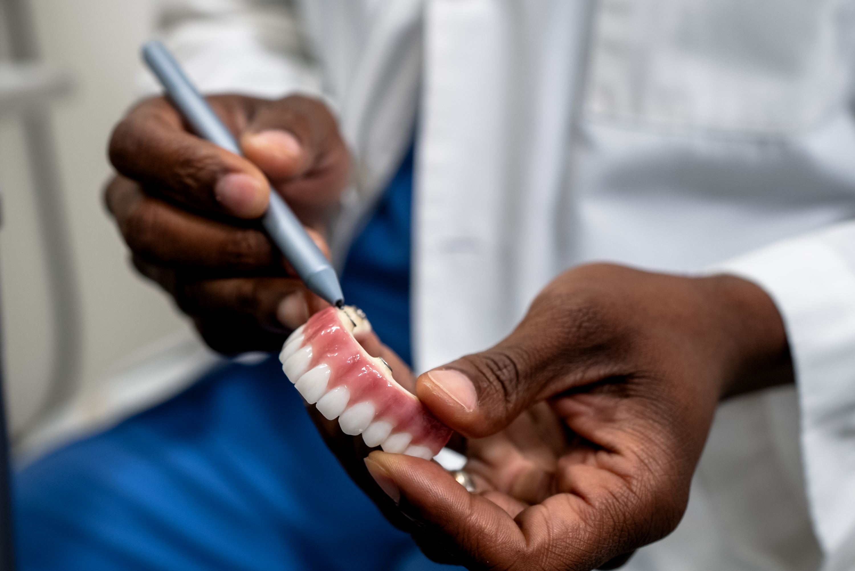 An AOMS clinician holding a full-arch zirconia implant bridge