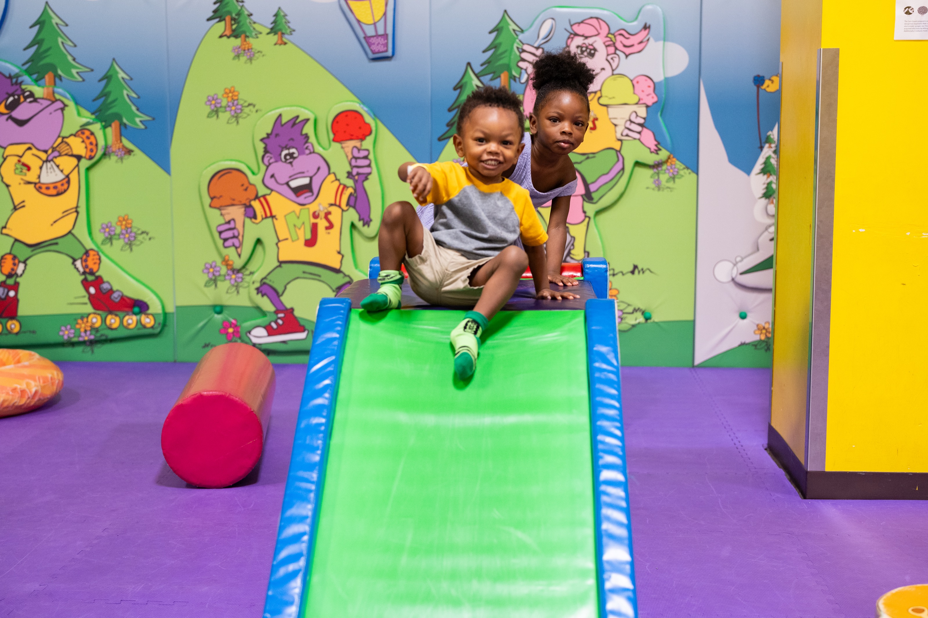 Two kids sliding together on the toddler slide