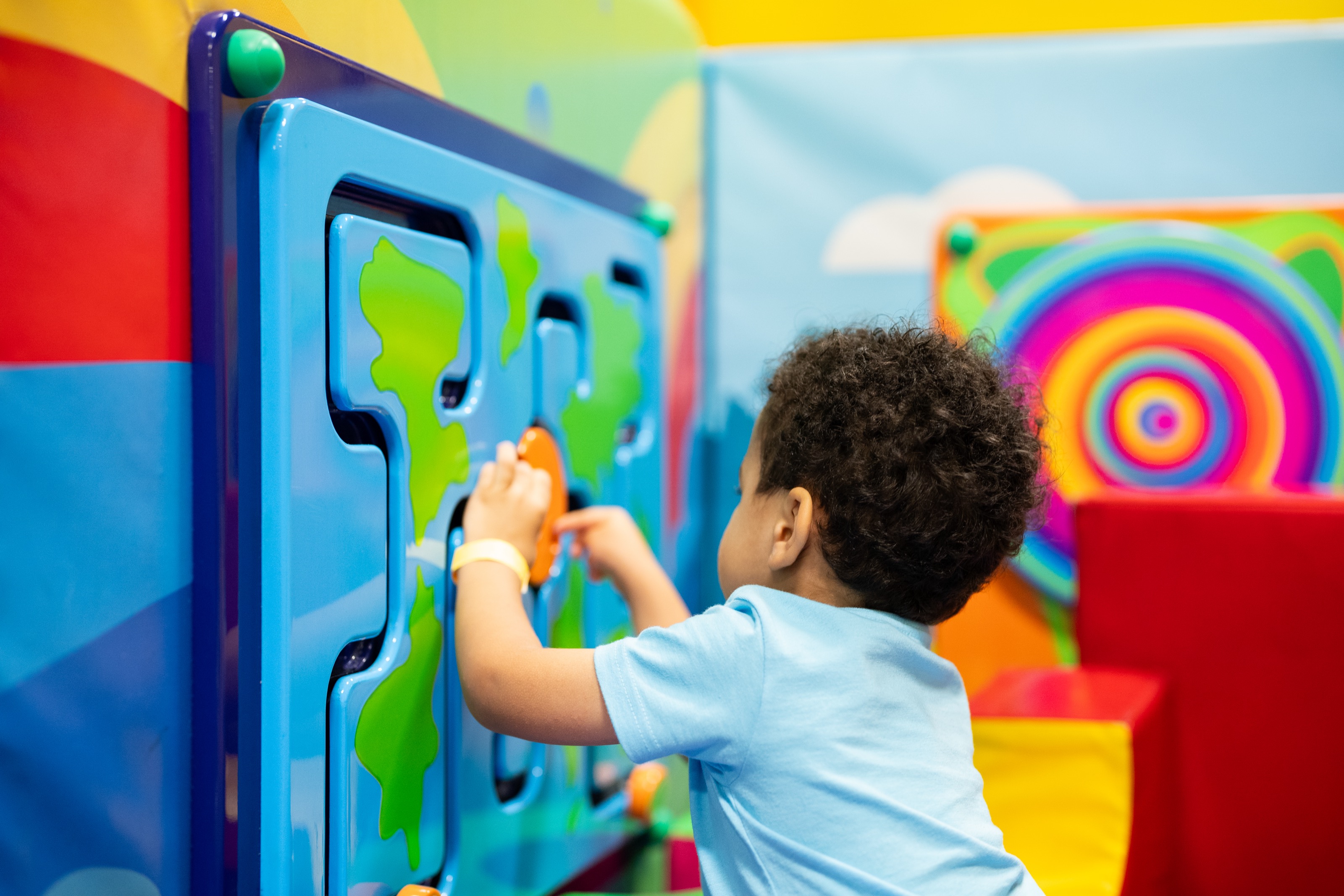 Toddler playing with colorful puzzle wall