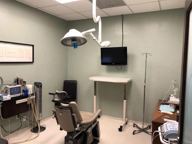 Surgical operatory with patient chair, overhead light, and monitor