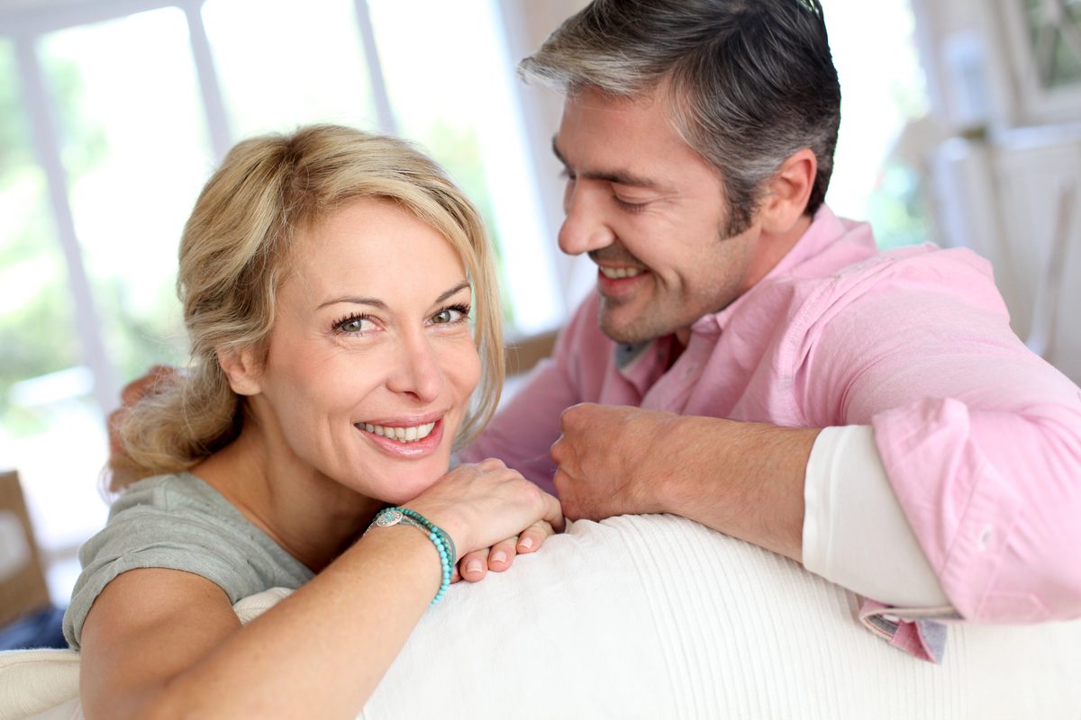 Smiling middle-aged couple relaxing together on a sofa at home