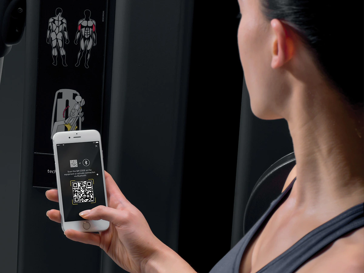 Vendég telefonjával Technogym gép QR-kódját olvassa be a LevelOne Fitness edzőtermében