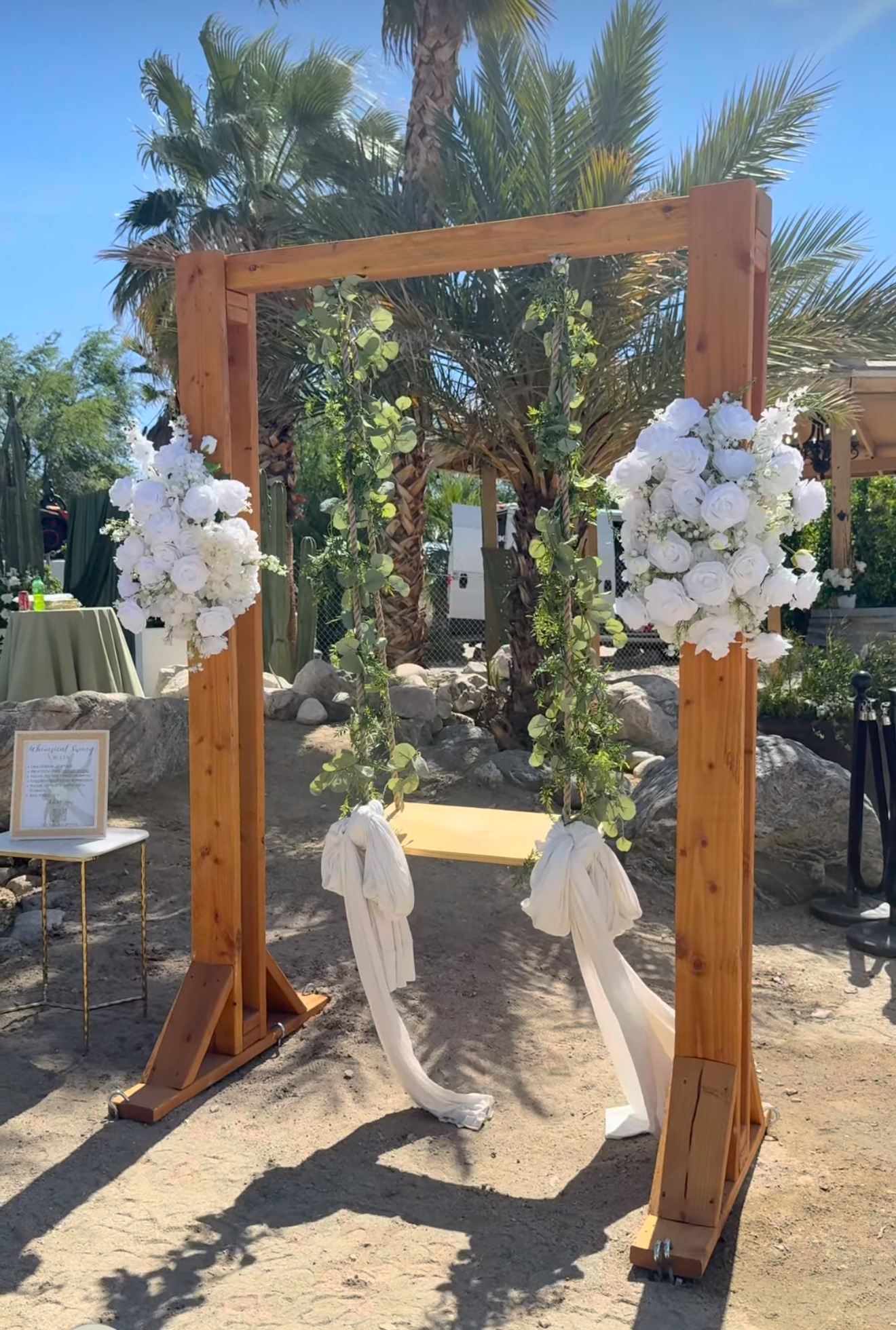 Wooden wedding arch decorated with white flowers and greenery