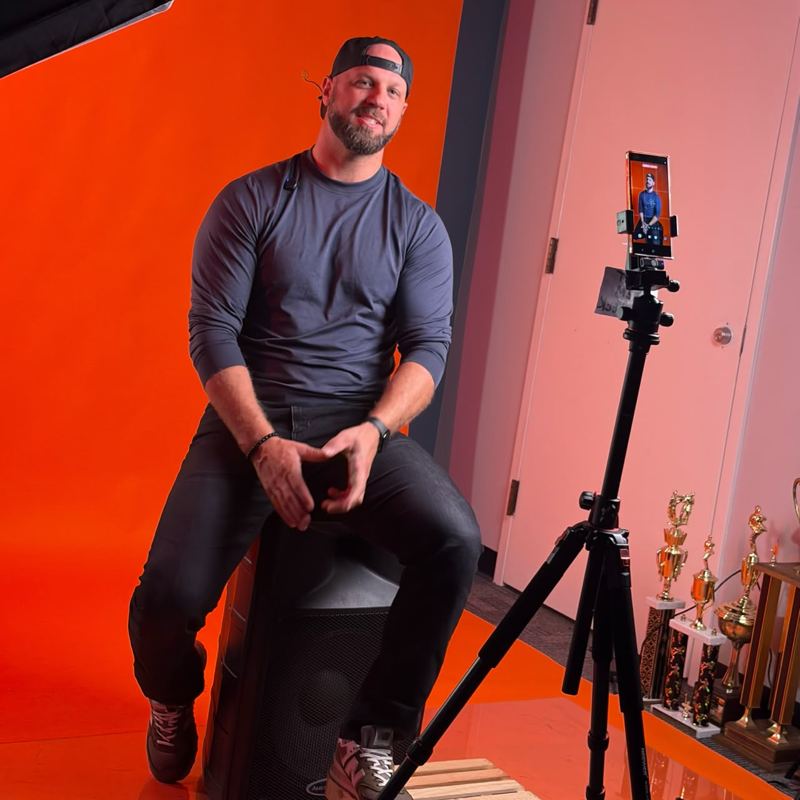 Me sitting in front of an orange backdrop with a phone on a tripod