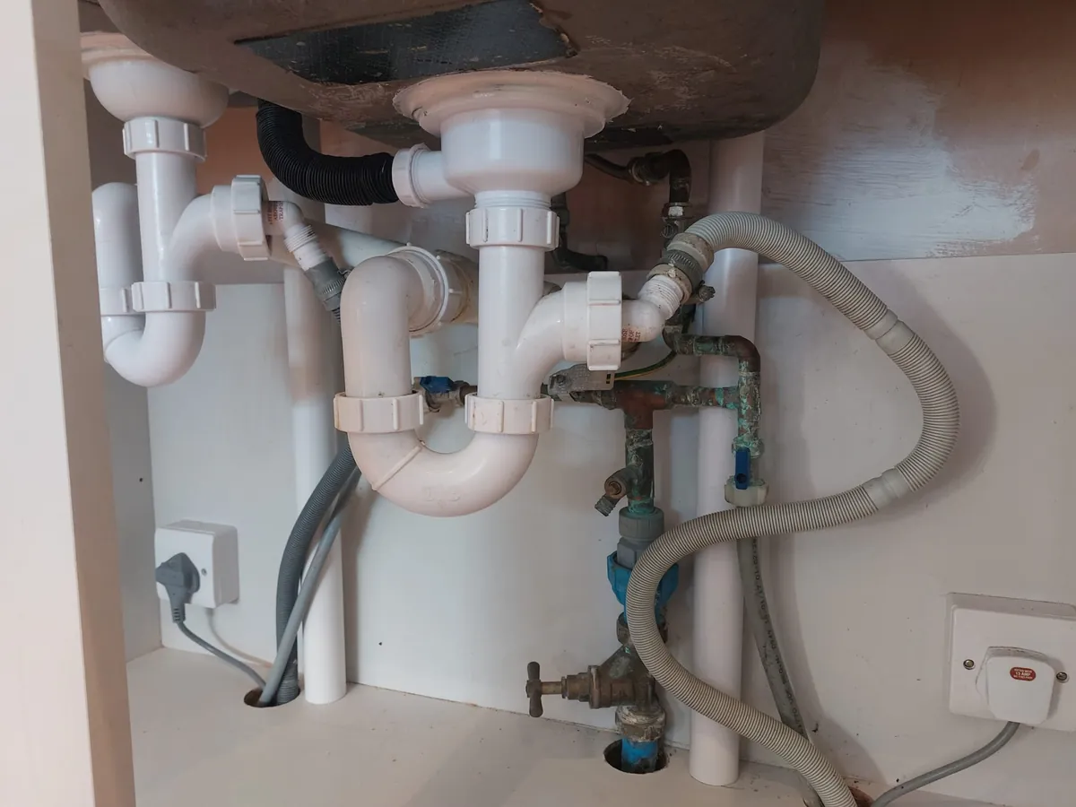 Plumber in Coventry: waste pipes and valves under a kitchen sink