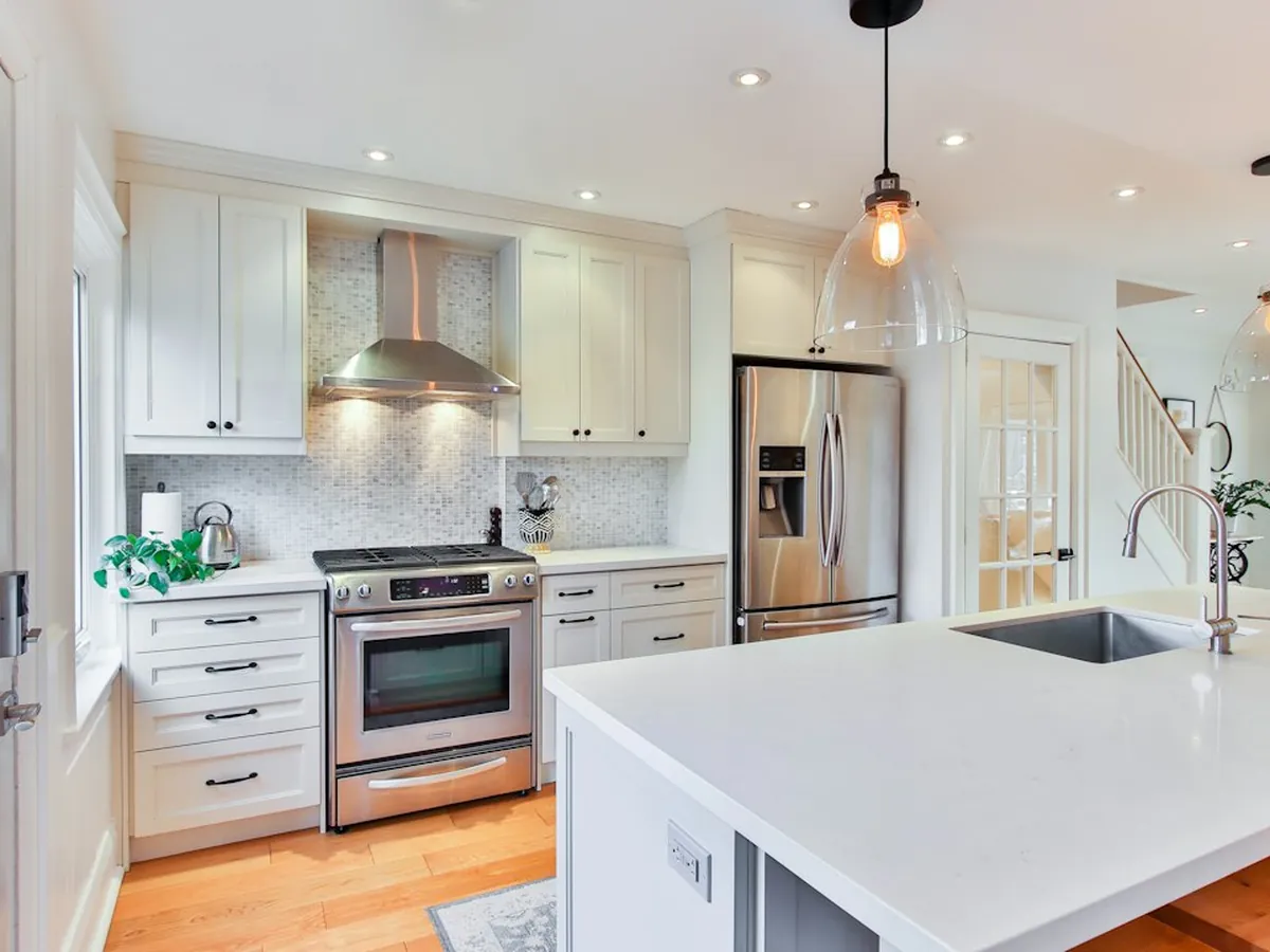 White shaker kitchen with a quartz island, sink and pendant lights