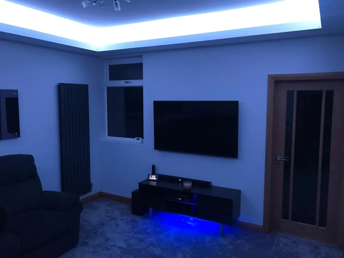 Living room with LED cove ceiling lighting, wall-mounted TV and radiator