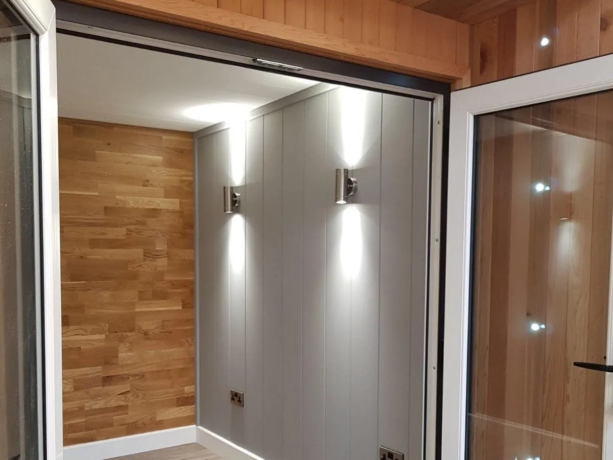 Steel wall lights, LED downlights and double sockets in a panelled room