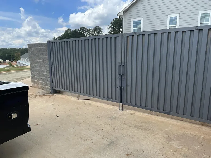Dark metal sliding gate running alongside a block wall enclosure