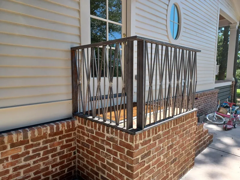 Decorative metal balcony railing on a brick and siding house