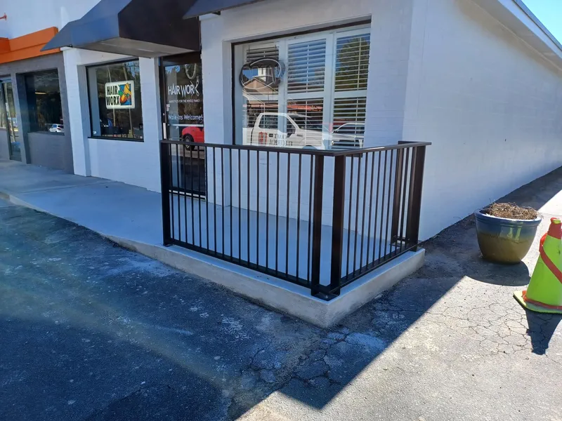 Black metal railing enclosing a raised patio at a storefront